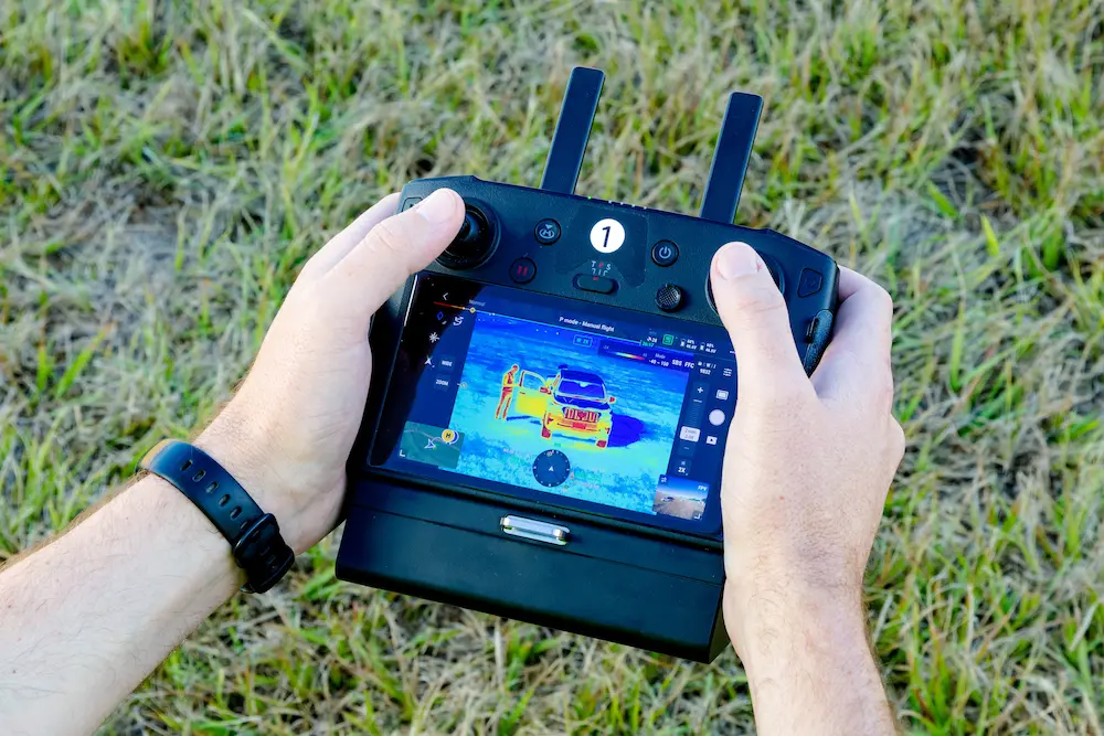 A hand is gripping a remote controller for a drone