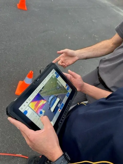 A hand is gripping a remote controller for a drone