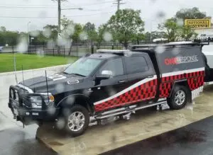 A black pickup truck with a red stripe stands in the middle of the rain