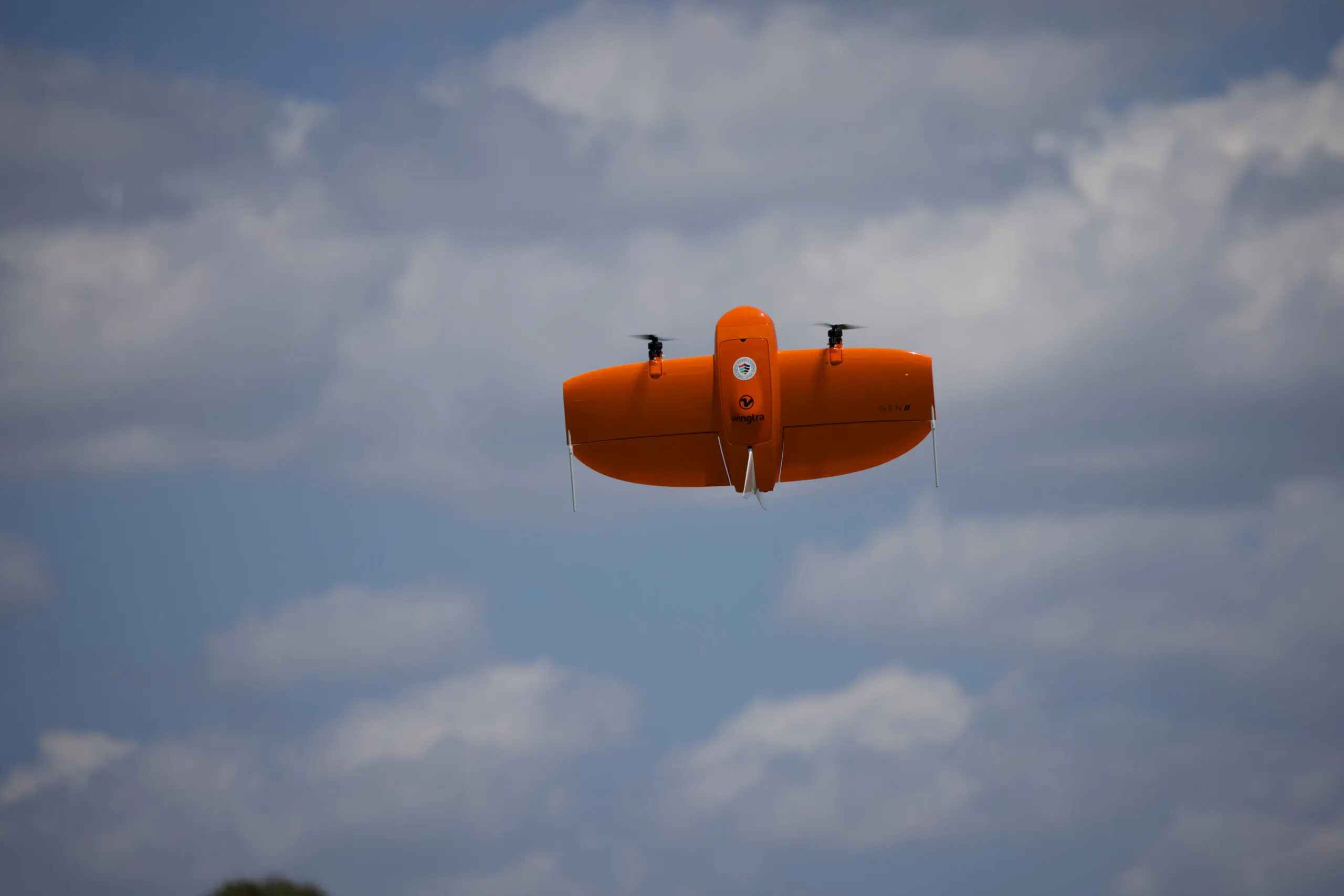 An orange rocket shaped like an airplane soars through the sky