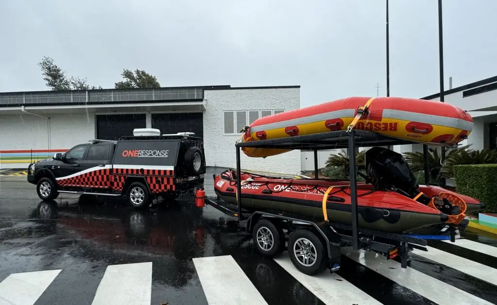 A black pickup truck is pulling a red inflatable boat