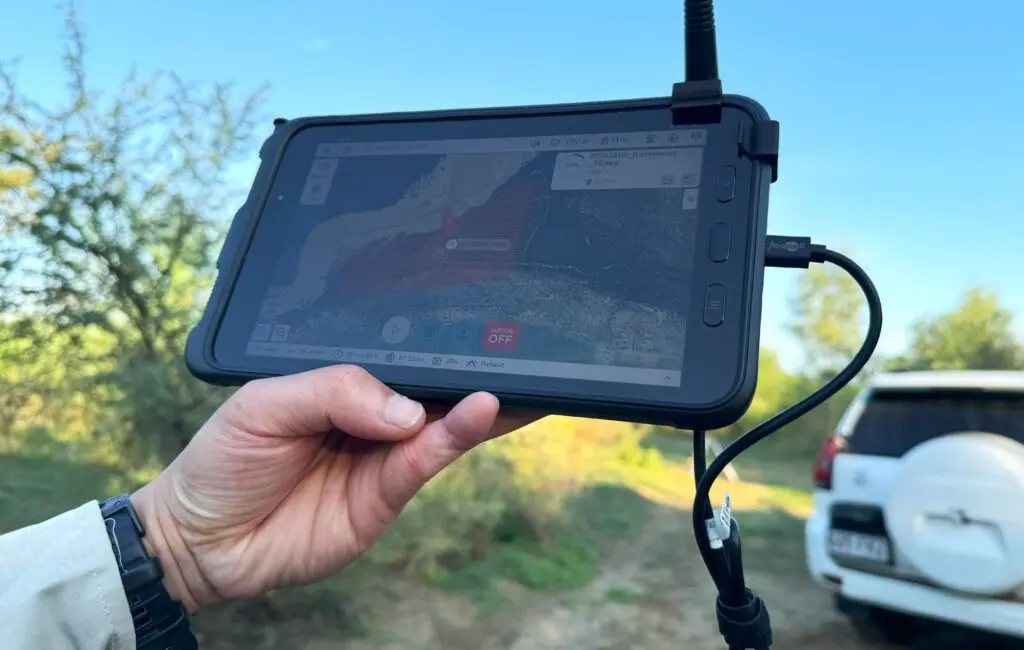 A hand is gripping a remote controller for a drone