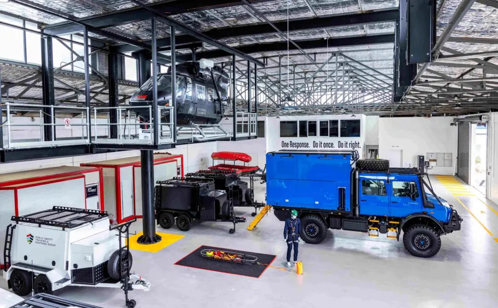 The security robot is standing in front of the blue car inside the building