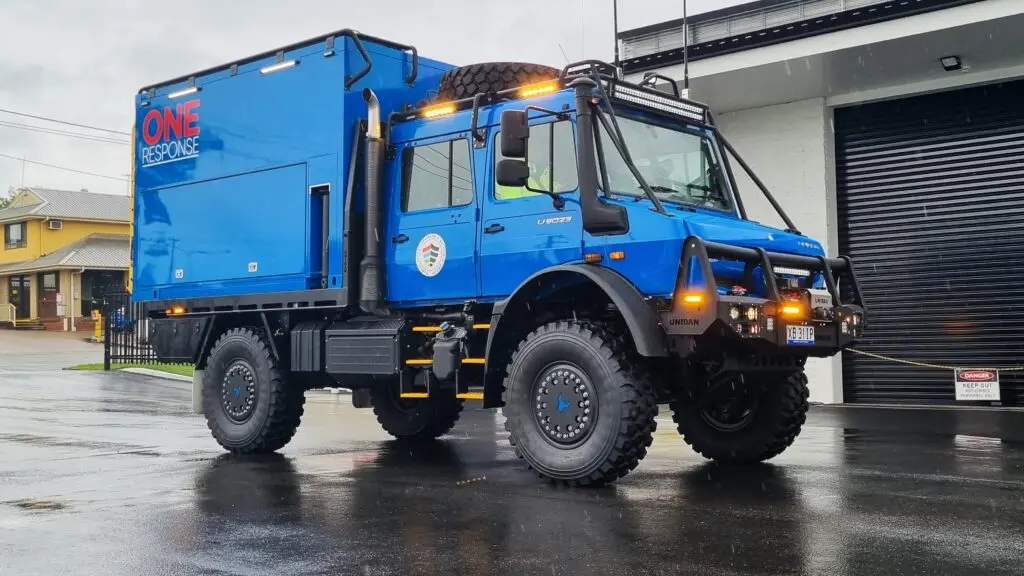 A blue truck stands in the middle of a rainstorm