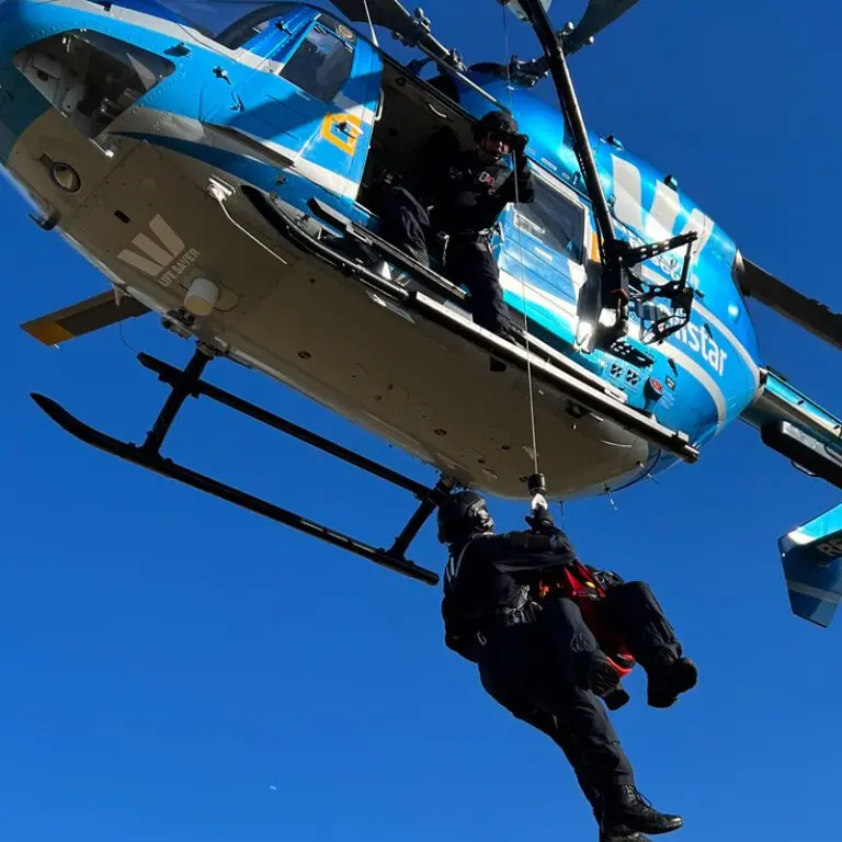 Two people are suspended from a helicopter in midair